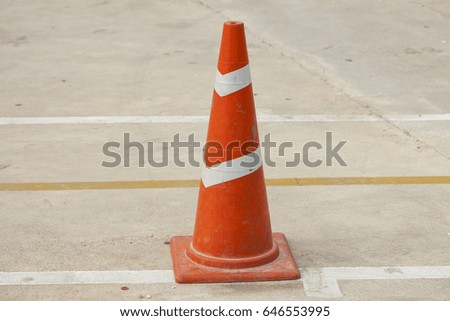 traffic cone, with white and orange stripes on gray asphalt.