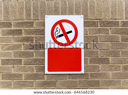 A no smoking sign on an outside brick wall 