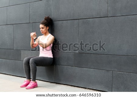 Athlete doing wall squat on city street Royalty-Free Stock Photo #646596310
