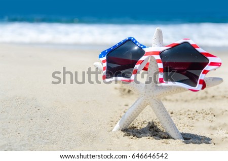 Patriotic USA background with starfish in the sunglasses on the sandy beach