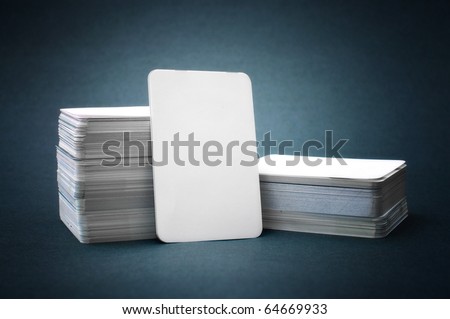 Business cards with rounded corners. Pile of blank business cards lays propped up another business card.