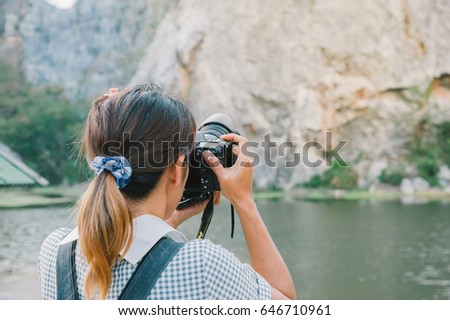 Back of professional travel photographer with camera while shooting landscape.
Young woman taking photo of mountain.
woman photographer taking photo at the lake.
