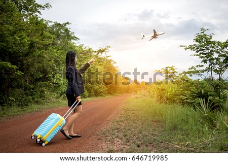 A beautiful young businesswoman With luggage Walk to the airport on a dirt road in the woods.