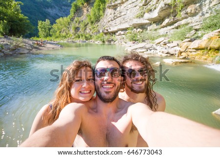 Enjoying pool party with friends. Group of beautiful young people looking happy while taking selfie photo in natural pool reserve in the riverside