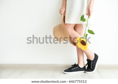 Girl holding sunflower and straw hat on white background