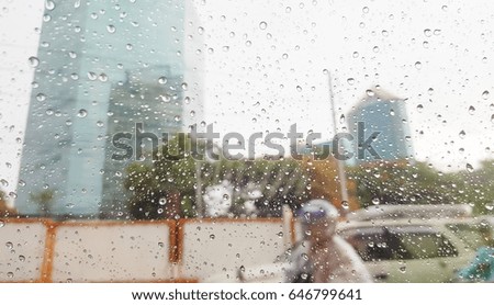 Raindrops on car window with road traffic and building background
