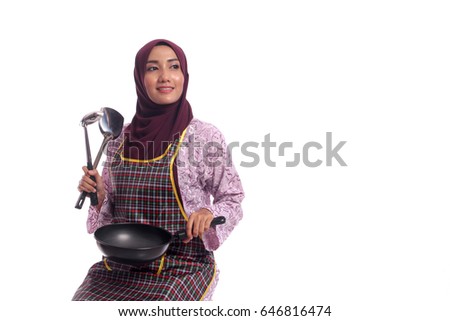 muslimah model in fashionable dress with apron,holding spatula and pan isolated in white background