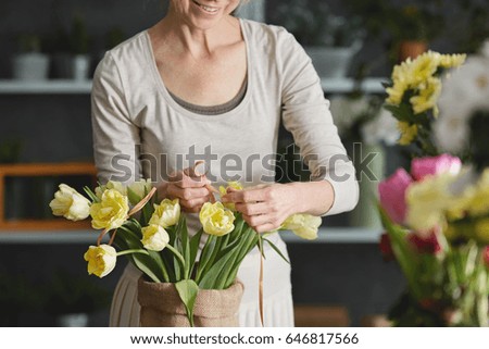 Woman decorating bouquet of yellow tulips in sack