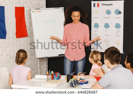 Smiling native speaker during French lesson with kids/Native speaker during French lesson/My name is ...