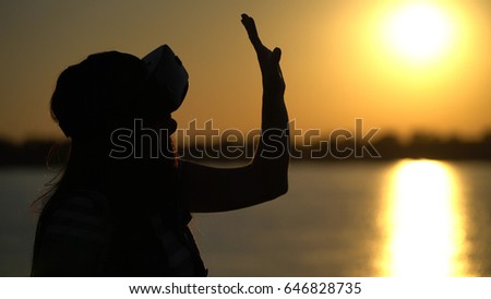 Woman in virtual reality glasses on the sunset background
