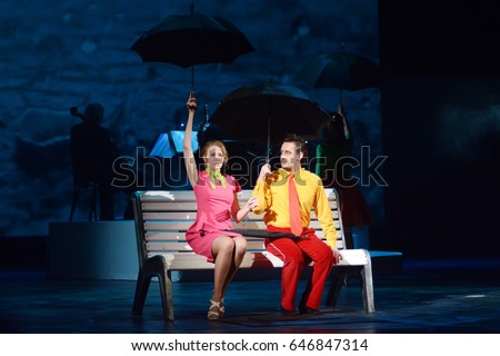 Guy with a girl sit under the umbrellas on a bench Royalty-Free Stock Photo #646847314