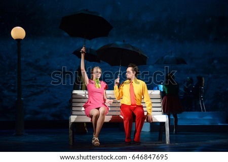 Guy with a girl sit under the umbrellas on a bench Royalty-Free Stock Photo #646847695