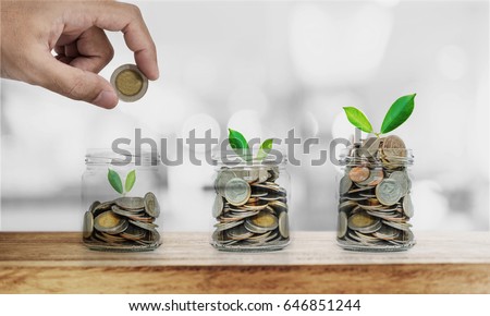 Hand putting coin in glass bottles with plants glowing, Saving money , investment and economize  concepts Royalty-Free Stock Photo #646851244