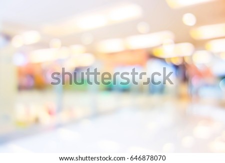 Blurred background of people shopping at department store mall with bokeh lights.