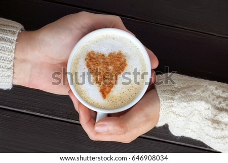 Foamy cappuccino with a heart symbol in warm embraces/ Romantic coffee break for couple