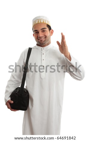 A man wearing a beautiful embroidered robe, thobe, kurta outfit fastened with ruby buttons and wearing a decorative topi hat.  He is waving in a friendly manner.  White background. Royalty-Free Stock Photo #64691842