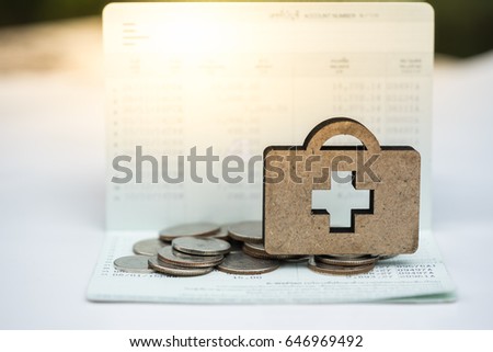 Wooden medical bag on coins stack on bankbook. Concept of money saving, financial, life insurance, retirement, investment.