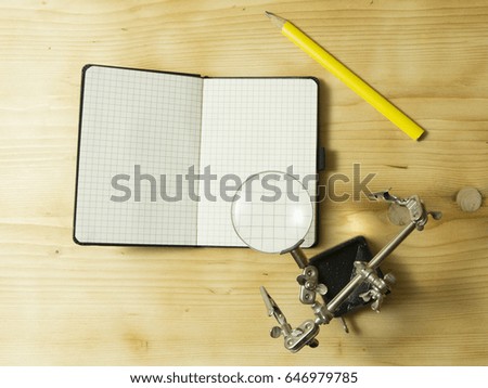 Magnifying glass and notebook on wooden table exploration