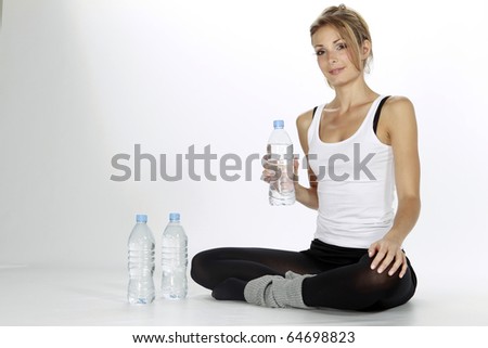 Pretty blond lady drinking water after sport isolated in a white background