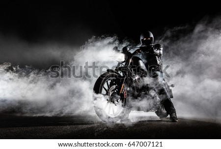 High power motorcycle chopper with man rider at night. Fog with backlights on background.