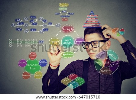 Smart man analyzing human needs and hierarchy writing self development plan on gray wall background Royalty-Free Stock Photo #647015710