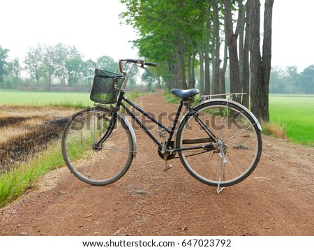 An old bicycle parked on a dirt road in the countryside, With the color scheme of the old retro picture