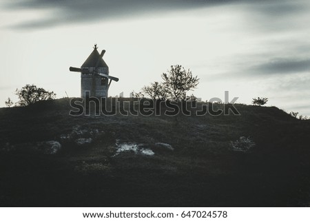A gloomy landscape of an old abandoned windmill on a stony hill