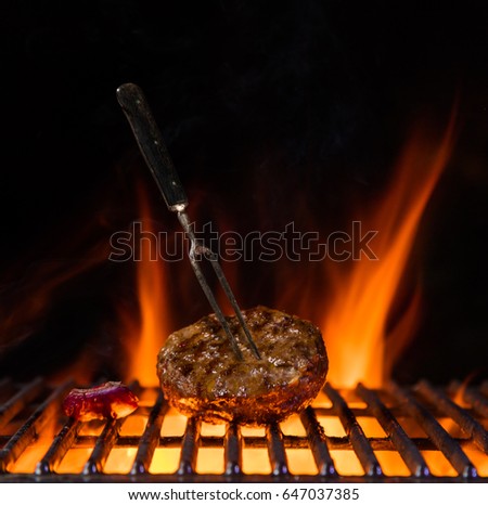 Beef milled meat for hamburger placed on the grill grate, flames on background. Barbecue and grill, delicious food.