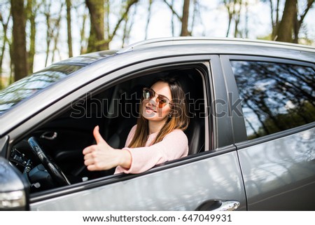 Woman sitting in the car and showing thumbs up