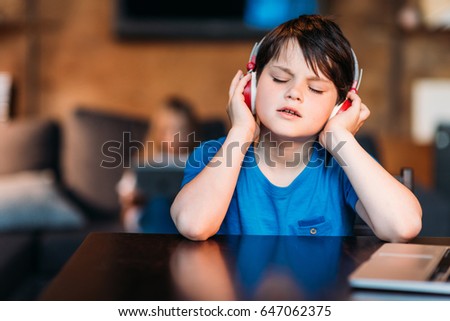 portrait of concentrated little boy listening music in headphones