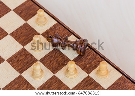 chess game. abstract composition of chess figures in chessboard isolated on light background. black king surrounded white pawns. top view
