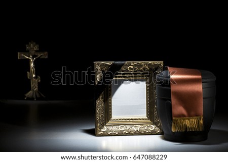 black cemetery urn with blank mourning frame and Orthodox cross on dark background