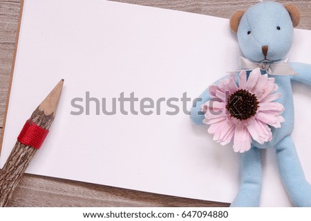 Stock photography flat lay template wooden pencil blank sketch white paper blue bear doll purple flower