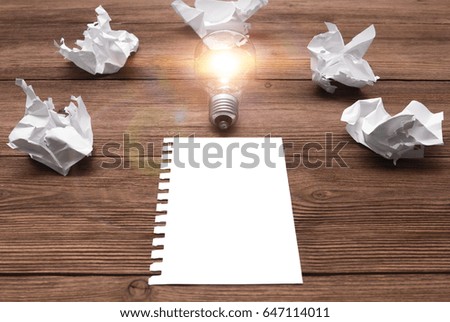 A great concept idea with crumpled paper and a light bulb on a wooden table. With white sheet inscription. The lamp caught fire from this idea. Symbol, concept of business, creative new idea. mock up