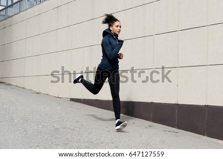 Fit brunette woman running in the city Royalty-Free Stock Photo #647127559