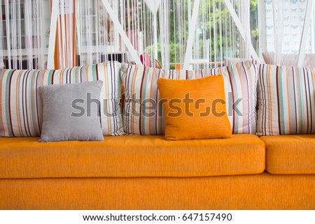 Orange modern couch with pillows on white wall