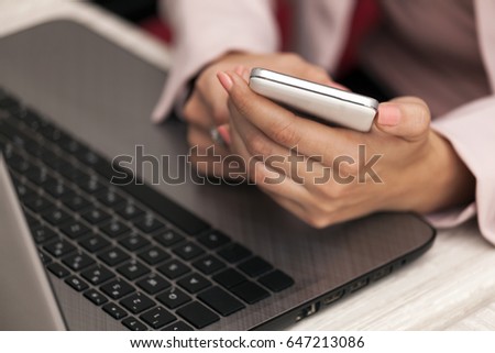 Close-up of female hands holding phone on a laptop