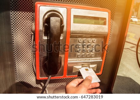 Calling using the public payphone. Red payphone on a city street. Royalty-Free Stock Photo #647283019