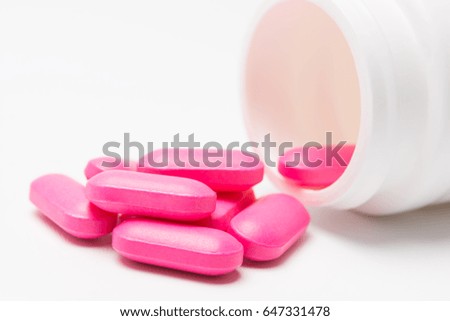 pink tablets of medicine pouring out of the bottle