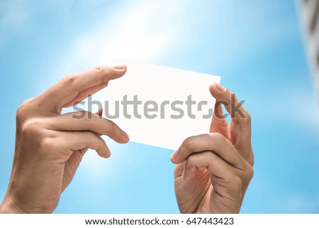 soft focus hands man holding blank business card for text on blue sky background