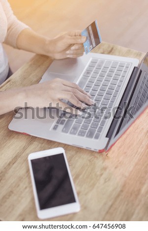 Woman hand holding a credit card and using a laptop to pay shopping online by credit card and smart phone on the desk