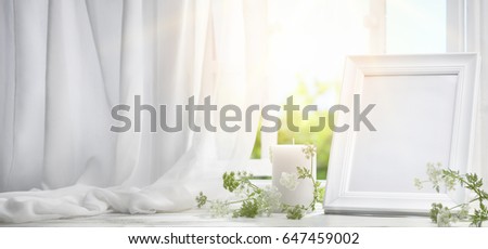 Picture frame near window with candle in the morning