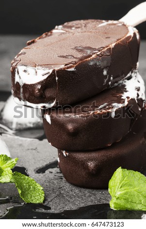 Vanilla ice cream on stick covered with chocolate glaze on a dark background