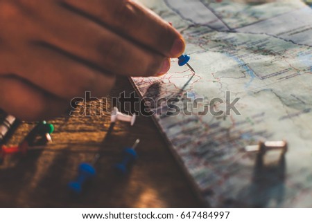 Close up hands putting pins to destination on world map. young male planning vacation. backpack travelling concept.