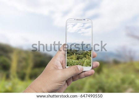 Male hand using smart phone with take photo at beautiful mountain in Thailand