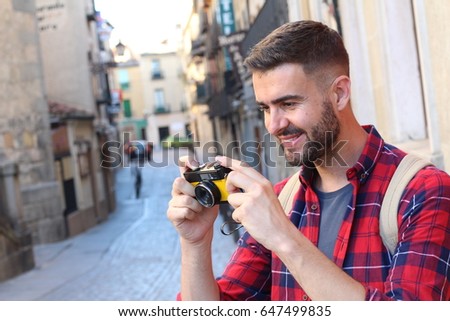 Handsome traveler looking at camera after taking a pic with a vintage film camera in a European town with copy space