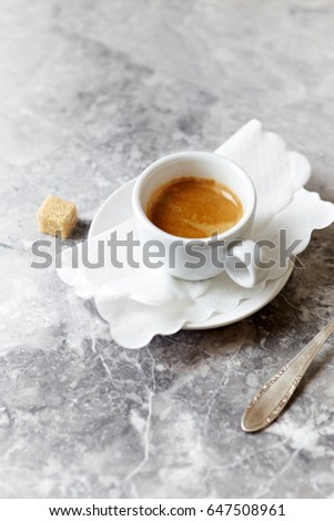 Cup of Espresso. Symbolic image. Cup of coffee and brown sugar cube. Bright stone background. Copy space.