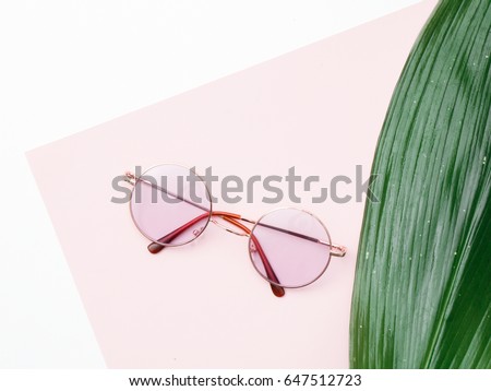 Minimal style. Minimalist fashion photography. Vintage. Glamour. Pink Sunglasses with a fresh Tropical leaf on a pink pastel background Royalty-Free Stock Photo #647512723