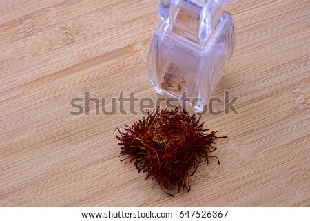 Selective focus of Dried saffron spice clear bottle with wood background.
