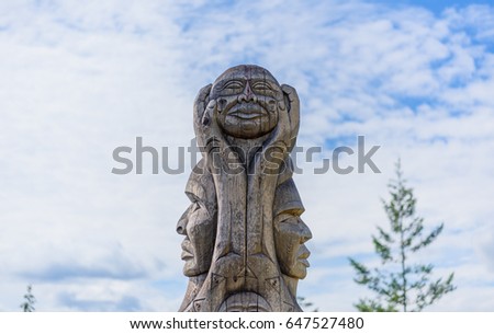 A wooden totem pole in British Columbia Canada at blue sky background